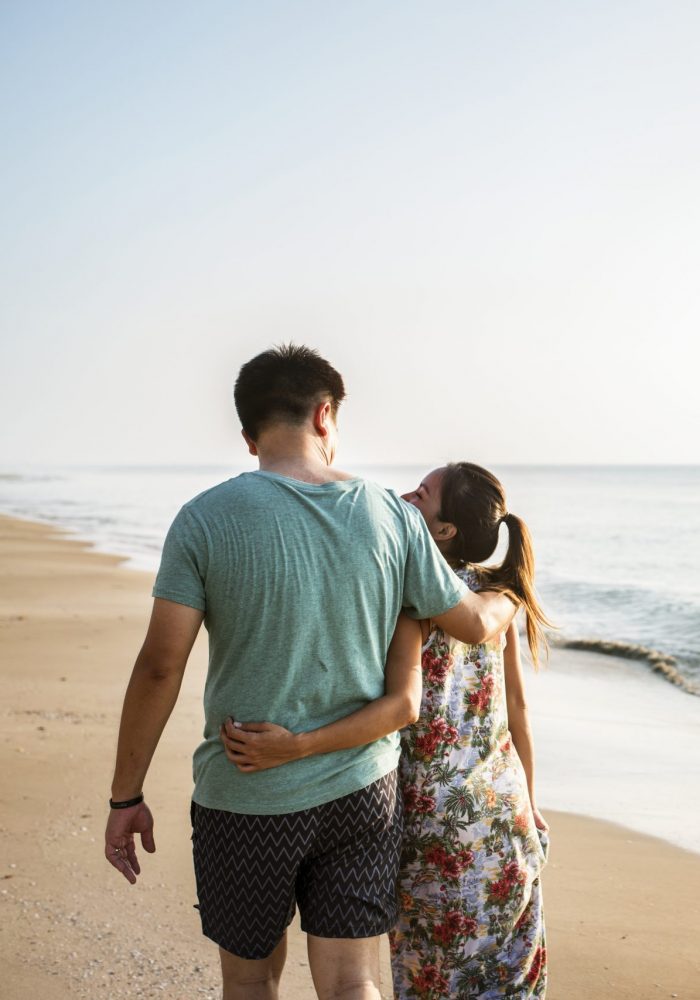 couple-walking-on-the-beach-M6QCF5A-scaled